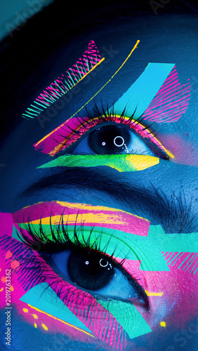 Close-up of eyes with vibrant, neon makeup and digital art effects.