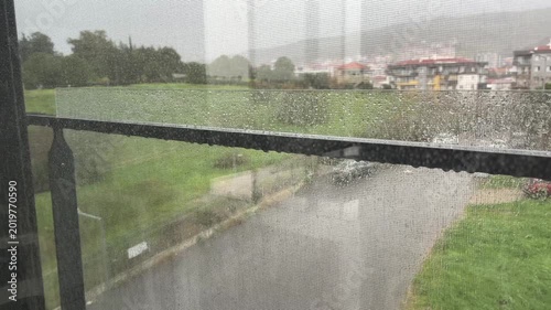 Real-time footage of heavy rain falling seen through a window screen