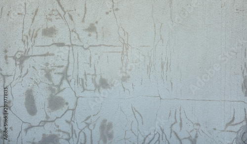 A close-up shot of an old textured concrete wall with multiple cracks and water stains over the surface