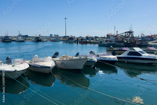 Bild auf Leinwand Colorful traditional fishing boats moored in the calm, reflective water of Setubal harbor, Portugal
