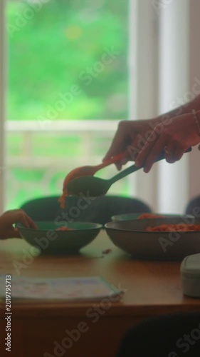 Close up of spaghetti being served onto plate during family dinner capturing nourishment, home cooking and authentic everyday mealtime routine