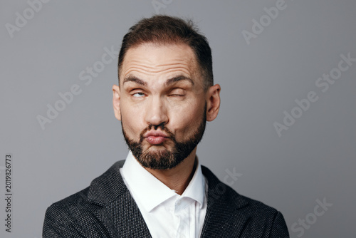 Billede på lærred A professional man in a tailored suit strikes a playful pose with puckered lips, set against an isolated colored background for a business scene