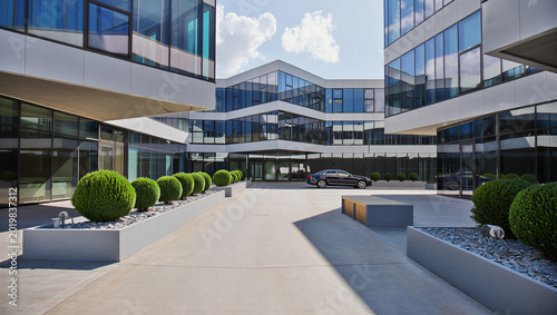 Canvas Print Contemporary glass office complex courtyard with manicured round topiary bushes