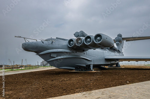 Large hovercraft on display in Dagestan, Russia near a park area with cloudy sky overhead