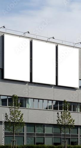 Grey office building with three blank white billboards on roof