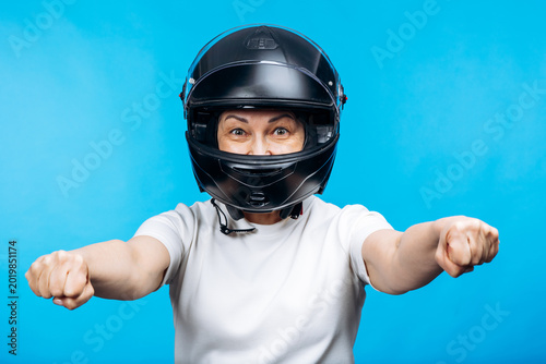 Foto Woman in a black full-face motorcycle helmet and white t-shirt, excitedly holdin