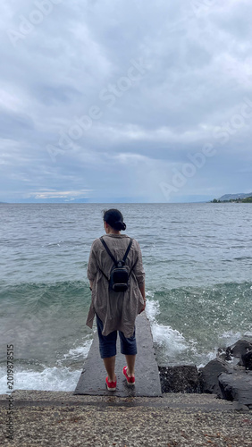 Woman walking towards the sea on a cloudy day
