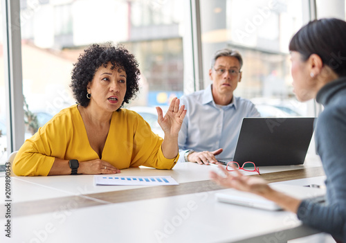 фотографія A group of businesspeople are gathered around a table, discussing something