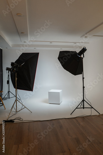 Bild auf Leinwand Professional photo studio setup with white cyclorama wall, softbox lighting equipment, and a white podium cube