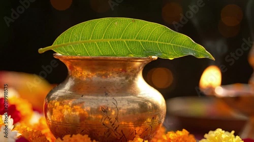 Traditional kalash pot with mango leaf and flame lamp, surrounded by marigold flowers, representing spirituality and tradition
