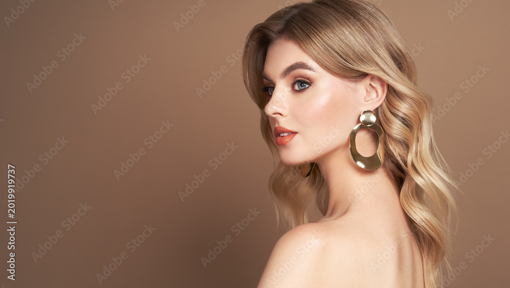 Fototapeta premium A beautiful young woman with shiny wavy blonde hair. Model with healthy skin, close up portrait. Cosmetology, beauty and spa