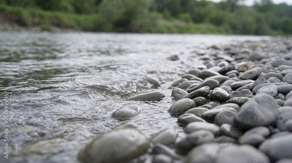 Fototapeta premium River water washing over smooth gray rocks. Nature background for environmental concept. Calm and peaceful outdoor scene.