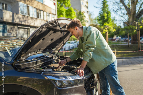 Obraz na plátně Man encountering car breakdown looking at vehicle engine