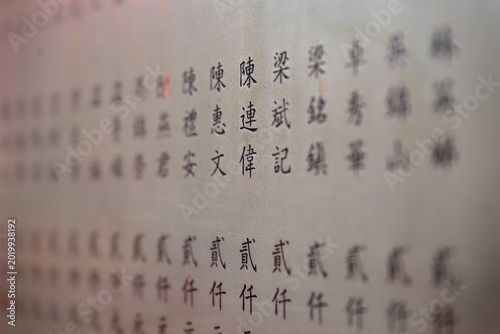Lamma Island, Hong Kong : shallow depth of field view of traditional Chinese characters written on a temple wall with selective focus on central calligraphy symbols. 