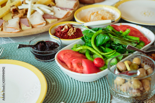 turkish breakfast served outdoors on sunny day, food variety, olives, jam, vegetables