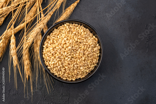Foto Wheat spikelets on a black stone background.