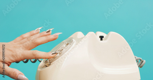 Fotografie Woman, hands and rotary dial with telephone in studio for retro phone call on a blue background