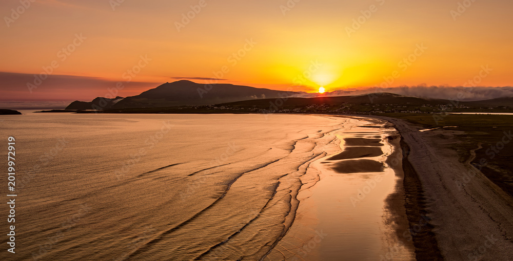Fototapeta premium Aerial sunset view of Keem Beach on Achill Island, County Mayo, Ireland. Golden Atlantic light over the horseshoe bay, sand and cliffs of the Wild Atlantic Way.