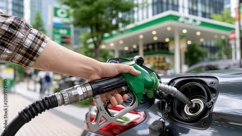 Close up of a hand holding a green fuel nozzle inserted into a car, transportation energy concept with modern refueling station atmosphere
