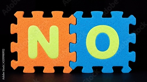 Colorful Puzzle Pieces Spelling the Word NO Against a Black Background.
