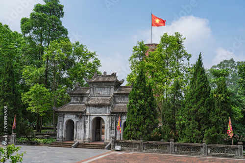 Historic gate and watchtower surrounded by lush trees at Son Tay Citadel in Hanoi under bright summer daylight.