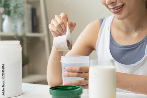 Bild auf Leinwand Young sporty woman pouring protein powder into a cup to make replacement food me