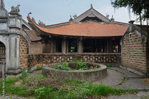 Traditional courtyard house with circular well at Duong Lam Ancient Village near Hanoi showcasing historic Vietnamese rural architecture.