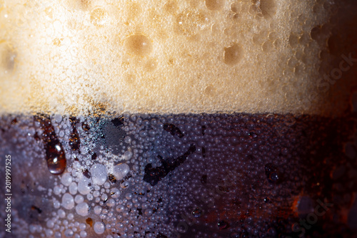 Photos Macro of dark beer or cola with thick foam and condensation droplets on glass,Cl