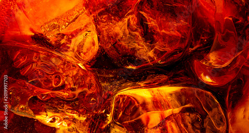 Foto Close up of ice cubes in cola soda drink with bubble and orange glow light effec