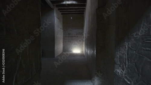 Corridor of Mereruka mastaba tomb at Saqqara, Egypt, with large painted red relief figure of tomb owner, smaller scene registers and dark doorway leading deeper inside.