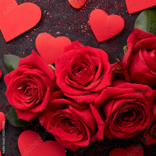 Red Roses Arranged Closely With Heart Shapes Surrounding Them on a Dark Backg...