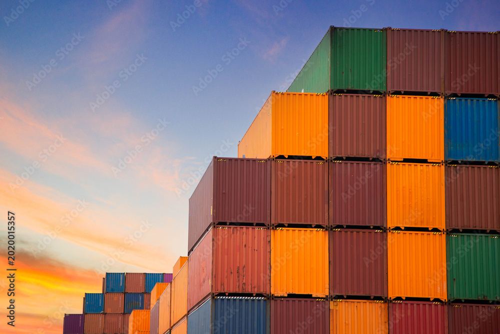 Fototapeta premium Industrial shipping containers stacked against a beautiful twilight sky background. Global business logistics and transportation concept with multicolored freight containers.
