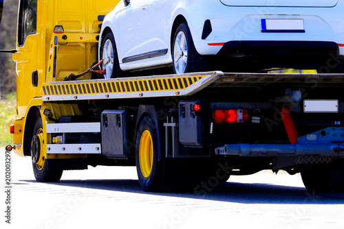 Yellow Flatbed Tow Truck Carrying White Car, Detail.