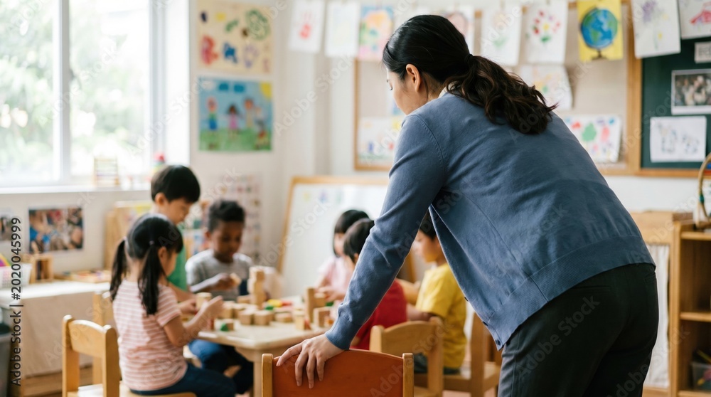 Fototapeta premium Busy preschool teacher guiding diverse children playing with wooden blocks at small table in bright classroom with artwork on walls, warm attentive scene of learning and collaboration