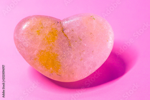 heart-shaped quartzite rock with pink background and shadow