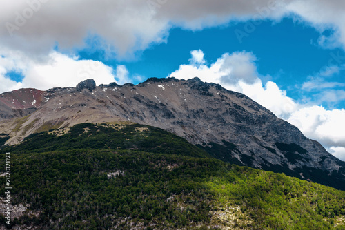 Panoramic view of jagged mountain ridges and dense green forests in the Andes.