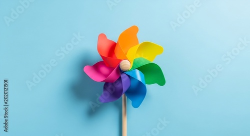 Colorful pinwheel on pastel blue background, playful childhood toy concept, vibrant summer decoration, minimal creative design