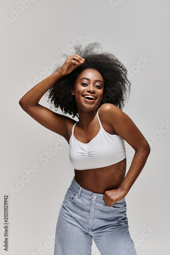 Quadro su tela Stylish young woman with curly hair showcasing confidence and fashion in a studi