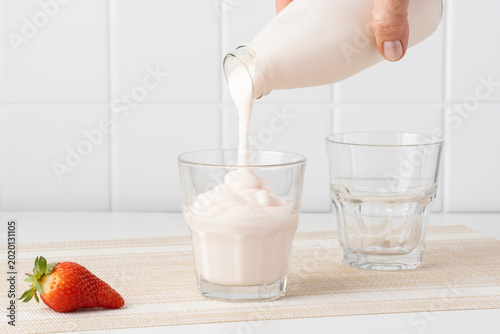 Foto Pouring homemade kefir, buttermilk or yogurt with probiotics