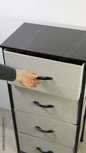 Vertical video of hand taking neatly folded blue towel from modern fabric storage dresser drawer. Close up. 4k footage.