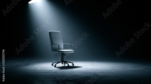 A single office chair sits alone in a dark room under a spotlight