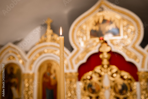Foto Burning wax candle close up with blurred golden iconostasis in Orthodox church i