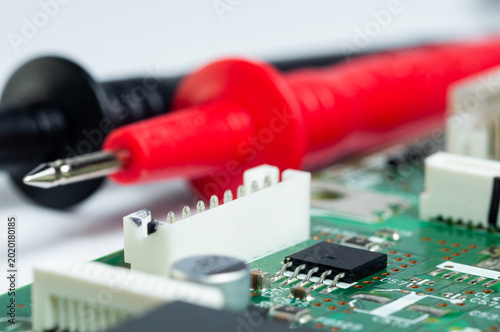 Fotografija Close-up of a circuit board with electronic components and a multimeter with test probes
