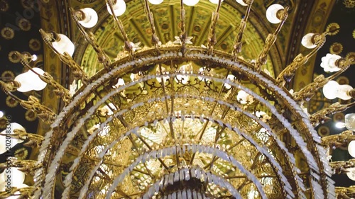 Slow motion 4K footage of an ornate mosque interior in Cairo, Egypt. The video captures a magnificent golden chandelier and richly decorated Islamic dome ceiling inside a historic travel landmark.