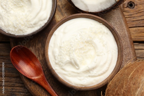 Fotografie Tasty coconut yogurt with flakes on wooden table, flat lay