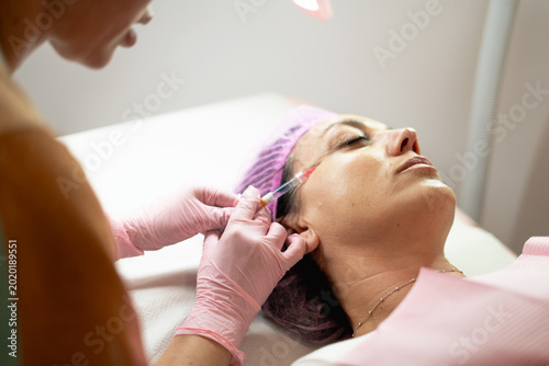 Fotografie Woman receiving facial filler injection for anti-aging beauty treatment