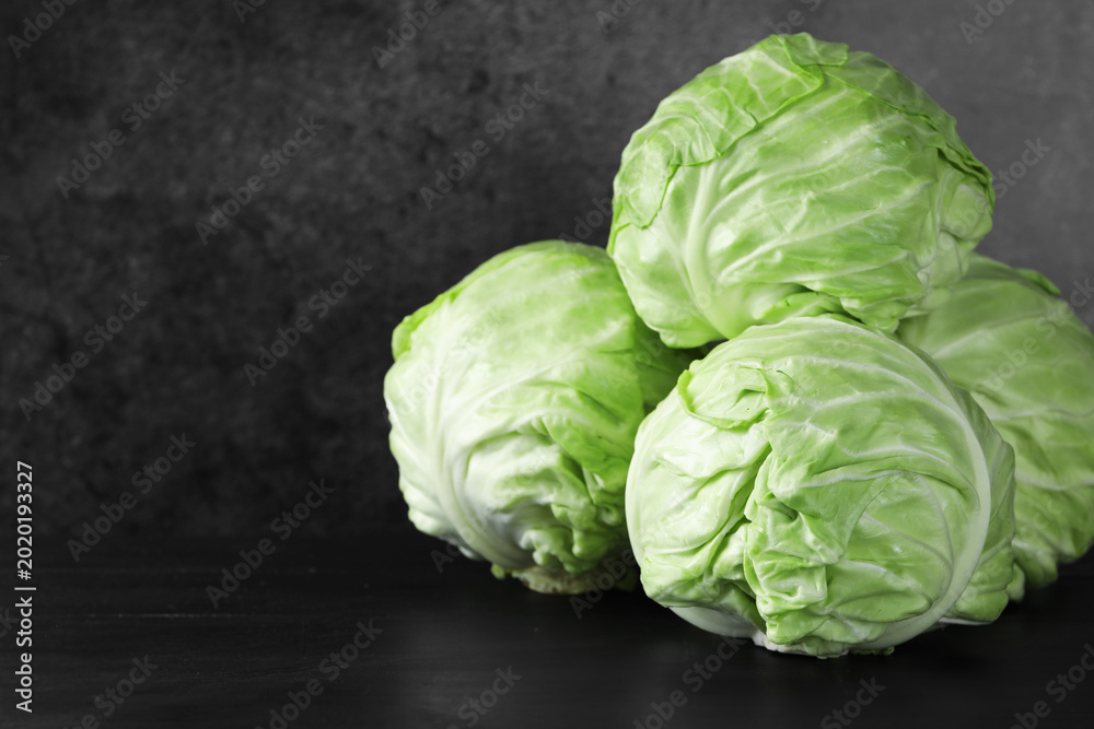Fototapeta premium Fresh ripe cabbages on black wooden table, closeup. Space for text