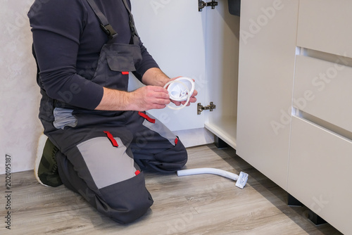 Cuadro en lienzo Professional plumber installing and repairing a kitchen sink drain pipe under a