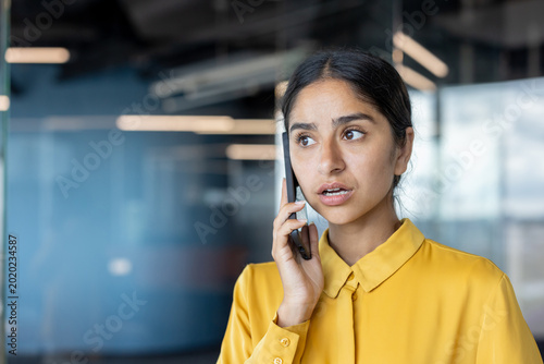 Photography Close-up photo of a serious young Indian businesswoman sitting in the office and