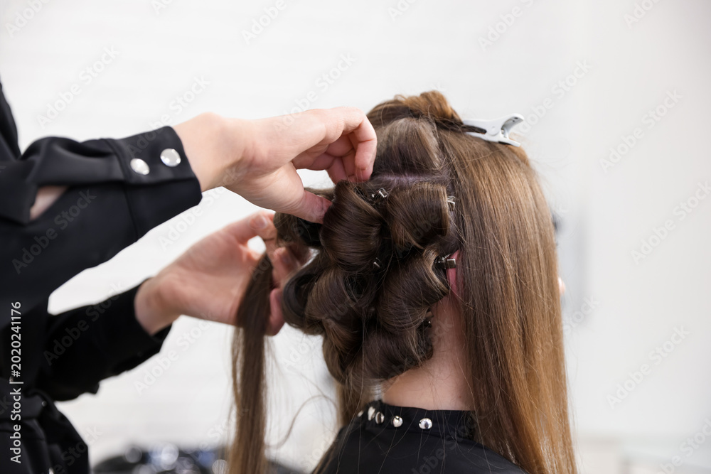 Fototapeta premium Hairdresser styling woman's hair in beauty salon, closeup